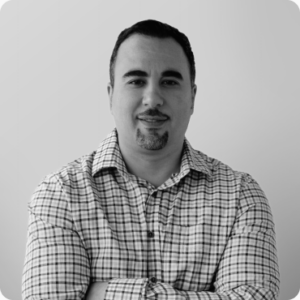 Touraj Rahimi, Founder and Digital Strategy Lead at Olibro Design, posing confidently in a checked shirt against a neutral background, representing expertise in digital strategy and technology.