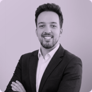 Touraj Rahimi, Founder and Digital Strategy Lead at Olibro Design, smiling in a professional suit against a light purple background, representing the core team dedicated to digital strategy and web agency services.