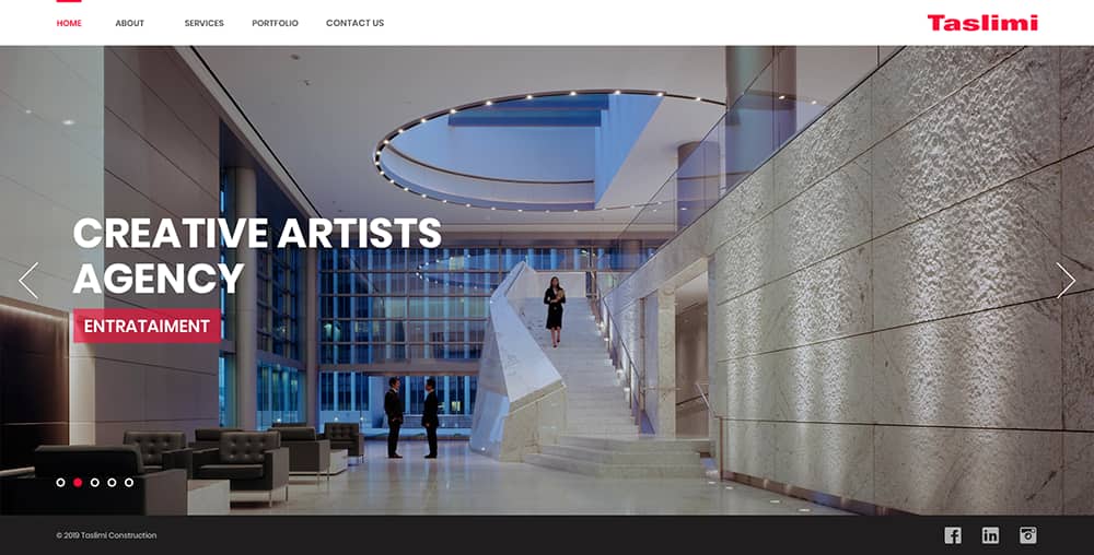 Interior of a modern building designed by Taslimi Construction, featuring a grand staircase, large glass windows, and contemporary lighting, showcasing a professional atmosphere for a creative agency.